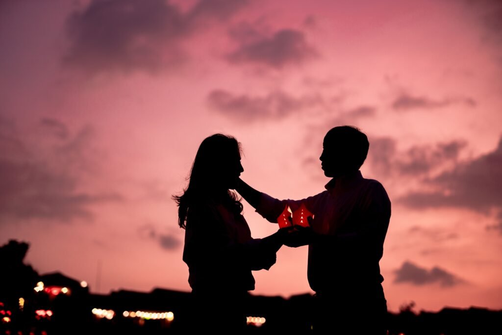 A romantic silhouette of a couple holding lanterns during a sunset, symbolizing love and connection.